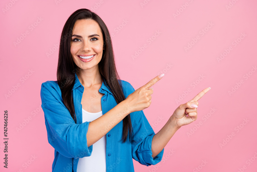 Photo of toothy beaming girl with straight hairdo dressed blue shirt indicating at offer empty space isolated on pink color background