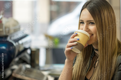 Charming girl with nice makeup having great time drinking cup of cappuccino