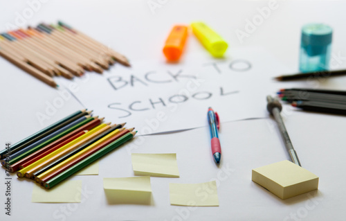 school accessories on a white background and white paper in the middle with "back to school' text on it. Concept for back to school, 