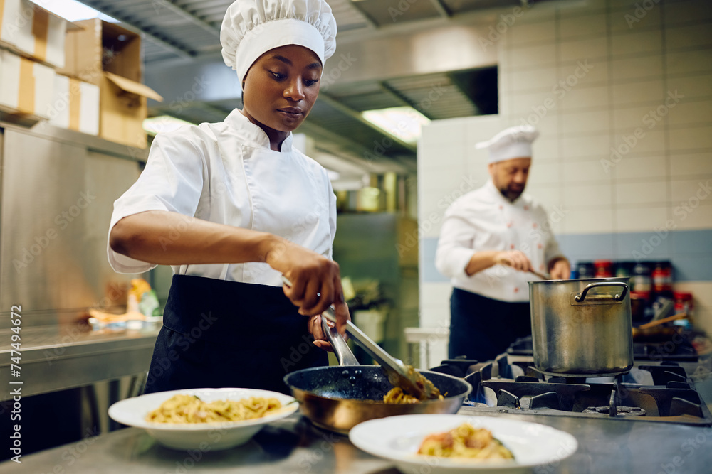 Young black cook preparing dish while working in restaurant. Young black cook preparing dish while working in restaurant.