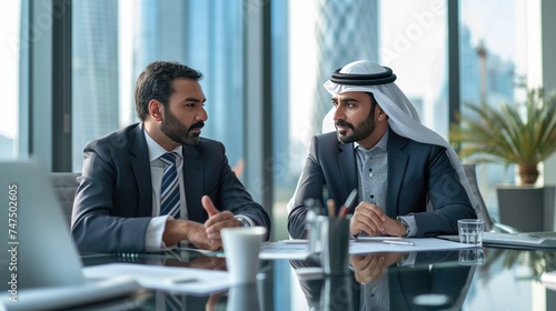 Consultation in Dubai, Two middle-eastern businessmen engage in a serious discussion at a modern office desk, with the cityscape of Dubai faintly visible in the background photo