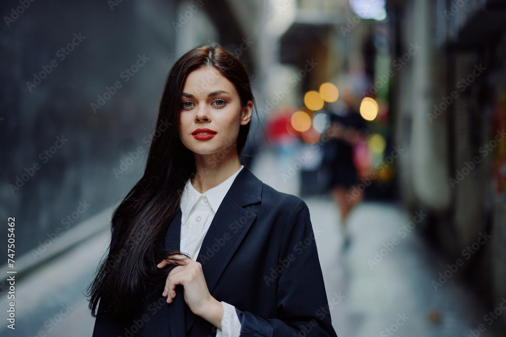 Fashion woman smile with teeth portrait looking at camera tourist in stylish clothes in jacket with red lips walking down narrow city street flying hair, travel, cinematic color, retro vintage style. Fashion woman smile with teeth portrait looking at camera tourist in stylish clothes in jacket with red lips walking down narrow city street flying hair, travel, cinematic color, retro vintage style.