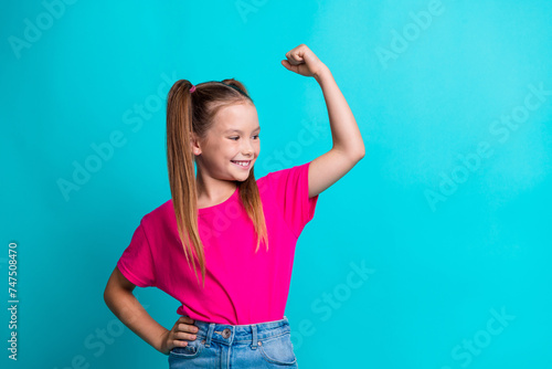 Photo of positive cute strong girl looking muscular arm biceps sport gym practicing empty space isolated on cyan color background