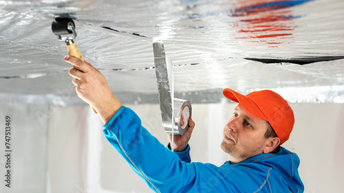 The builder is gluing the reflective aluminum tape over the vapor barrier. The vapor barrier as protection of thermal insulation against internal moisture.