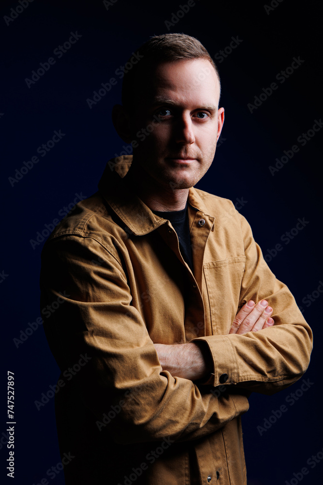 Portrait of a confident man on a dark background in a brown shirt. The emotion of concentration. A man without a smile Portrait of a confident man on a dark background in a brown shirt. The emotion of concentration. A man without a smile