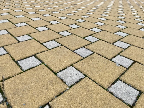 A detailed shot of a beige brick pavement with a diagonal pattern, showcasing the composite material and rectangle shape of the flooring