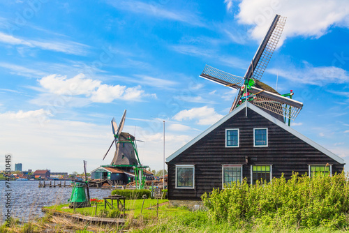 Dutch typical landscape. Traditional old dutch windmills against blue cloudy sky in the Zaanse Schans village, Netherlands. Famous tourism place.