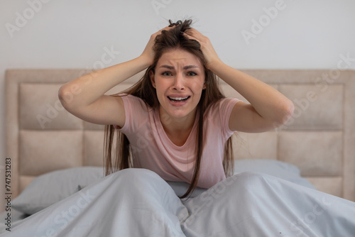 Desperate woman in bed touching head, crying out in frustration