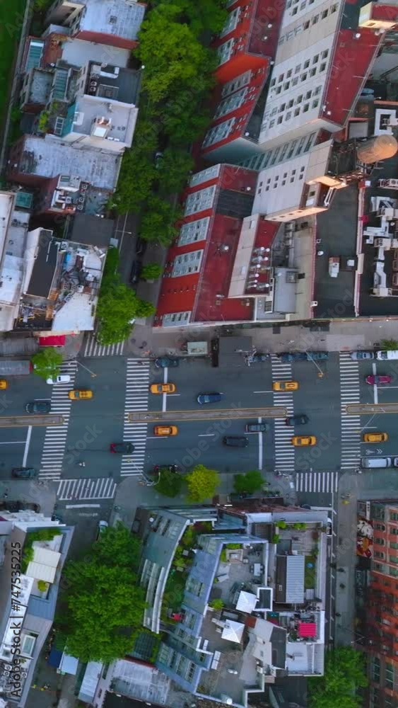Flying over the wide-lane road and crossroads with numerous automobiles moving along. View of the roofs of surrounding houses from top. Vertical video. Flying over the wide-lane road and crossroads with numerous automobiles moving along. View of the roofs of surrounding houses from top. Vertical video.