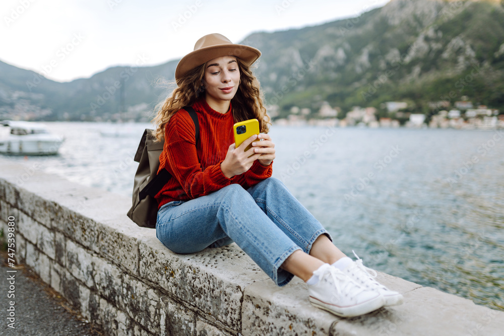 Young woman tourist uses a smartphone on the ocean shore. Lifestyle, travel, tourism, active life.