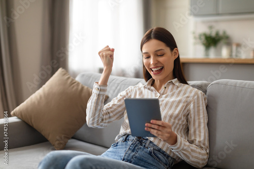Happy young woman celebrating success with tablet