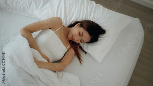 Beautiful asian woman have insomnia because of her period pain and cramp problem nightmare. She cannot sleep and stomach ache or menstruation. Young woman having period pain sleep troubles trying. photo