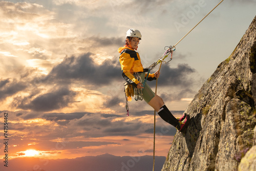 Person climbing in high mountains with yellow jacket rope and helmet in nature, confidence and risk, safety photo