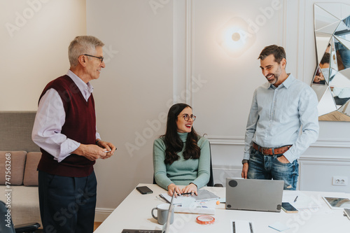 Canvas-taulu Two men and a woman enjoy a cheerful conversation in a bright office setting