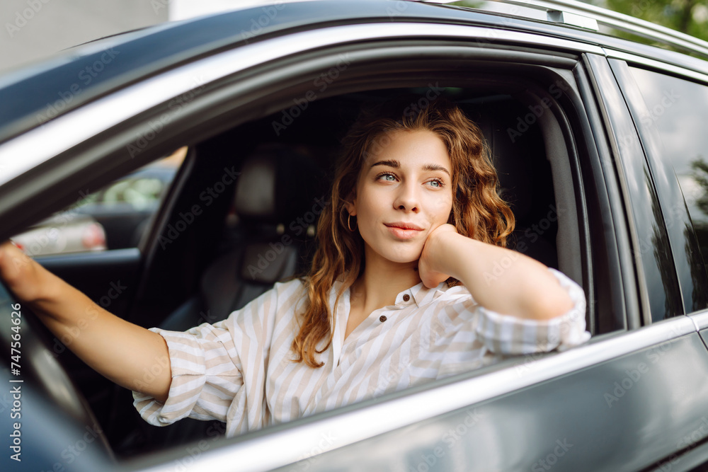 Female driver. Portrait of young beautiful woman in sweater sitting in the car. Car travel, tourism, carshering concept. Female driver. Portrait of young beautiful woman in sweater sitting in the car. Car travel, tourism, carshering concept.