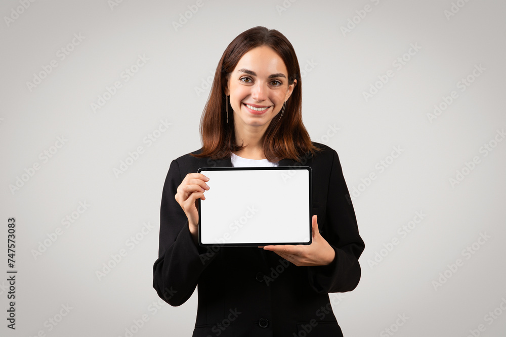 A cheerful, professional young woman confidently displays a blank tablet screen