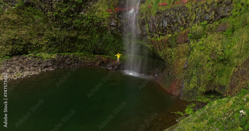 Traveler visiting in yellow jacket a waterfall. Hiking, travel to waterfall in nature on vacation or trip. Carefree, freedom, happy female hiker having fun and enjoying quality time alone on adventure Traveler visiting in yellow jacket a waterfall. Hiking, travel to waterfall in nature on vacation or trip. Carefree, freedom, happy female hiker having fun and enjoying quality time alone on adventure