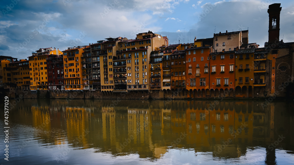 A serene view capturing the vibrant reflections of colorful facades of buildings on the calm water of a river, Firenze
