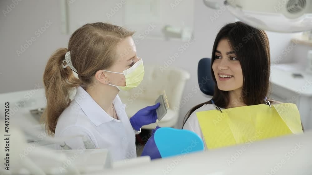 Dentist shares happy event, examines teeth, gestures with smile in dental chair. Dentist shares happy event, examines teeth, gestures with smile in dental chair.
