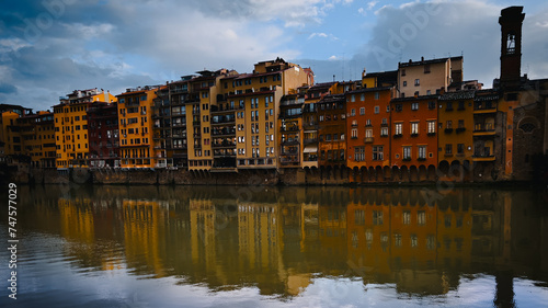 A serene view capturing the vibrant reflections of colorful facades of buildings on the calm water of a river, Firenze
