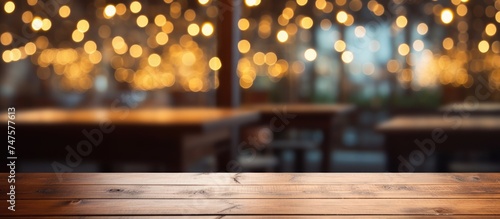 A wooden table top is shown against a blurred background of restaurant lights, creating a warm and inviting atmosphere. The lights in the background create a soft glow, photo