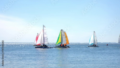 Sailing. Catamarans with colorful sails in open sea. Sports competitions on high seas. Regatta. Moving in wind on a sailing boat. Boat trip on yacht. Recreation, leisure, cruise. photo
