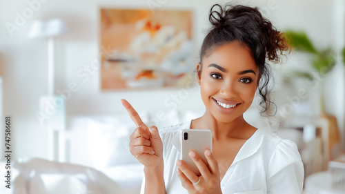 Mulher sorridente com um smartphone aponta o dedo para espaço vazio ao lado. Uso: publicidade, marketing, espaço para texto, tecnologia photo