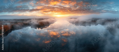 An aerial view of Lac de Saint Pardoux during an autumn sunrise  showcasing fog  clouds  and trees surrounding the picturesque lake.