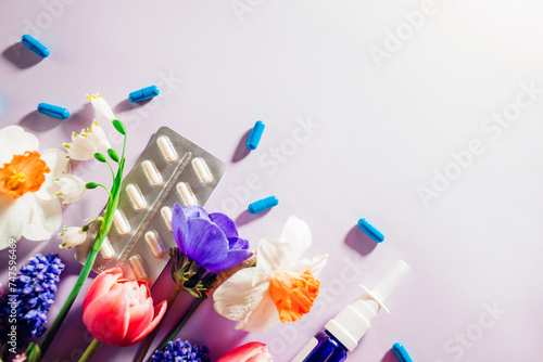 Seasonal spring allergy. Pills and nasal spray flat lay with purple flowers. Treatment for allergic to pollen people