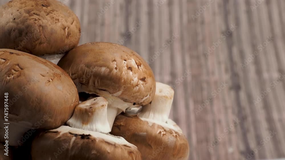 Champignon mushrooms rotate on a wooden background. Champignon mushrooms close-up. Champignon mushrooms rotate on a wooden background. Champignon mushrooms close-up.