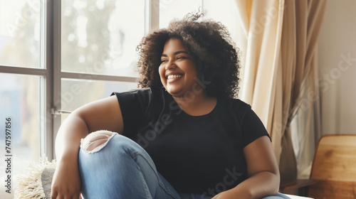 Feliz mulher afro-americana rindo enquanto está sentado na poltrona em casa