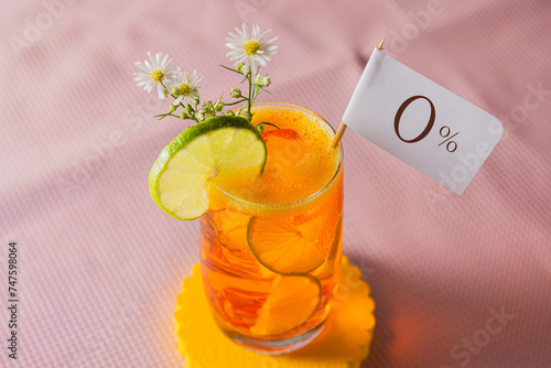 Close up of Orange drink with alcohol free pennant, slices of lemon and flowers on pink background photo