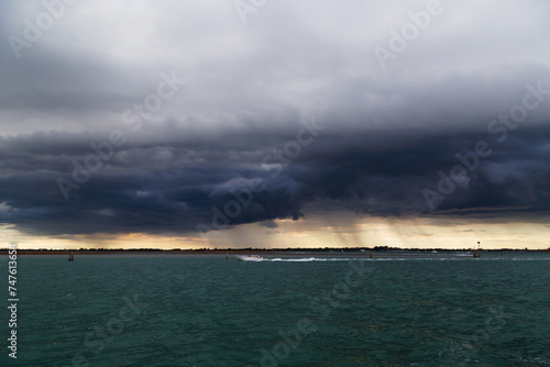 Uninhabited islands of Venetian lagoon and sea with dark stormy sky in background. View from Murano island, Venice, Italy