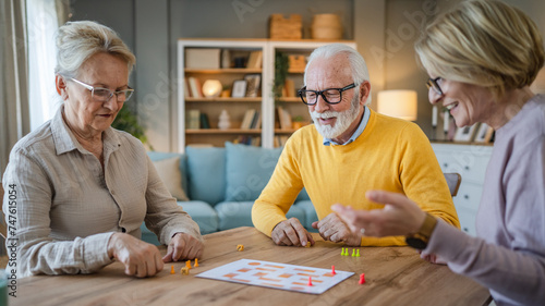 Group of people senior man and women play leisure board game at home