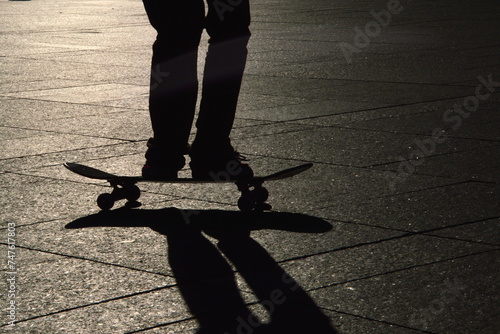 skater jumping on his skateboard with his shadow in evening backlight