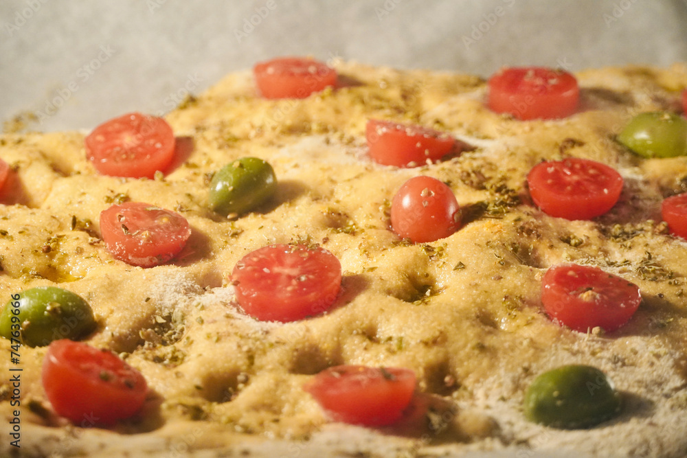 Typical Italian focaccia bread dough with tomatoes and olives is baked in the oven. Typical Italian focaccia bread dough with tomatoes and olives is baked in the oven.