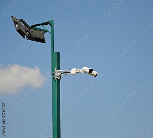 street lamp with CCTV cameras on a metal pole against blue sky. modern LED street lamp with cctv system. park lantern next to video surveillance system. security camera city street