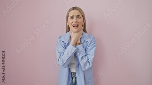 Young blonde woman in pain, suffocating from intense strangle over isolated pink background - health problem or asphyxiate concept photo