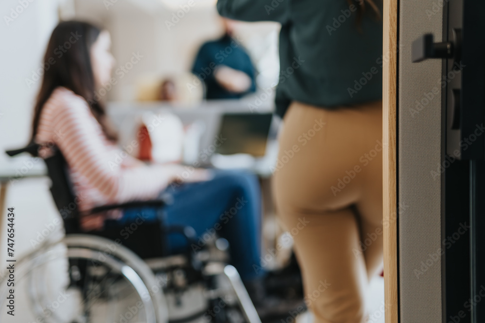 Handicapped female employee in wheelchair collaborating with her colleagues on a project at the office in a pleasant atmosphere.