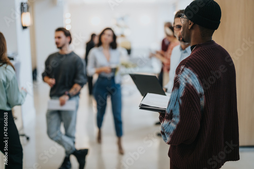 Wallpaper Mural Diverse group of businesspeople in informal attire conversing and walking in an office corridor, depicting a relaxed workplace culture. Torontodigital.ca