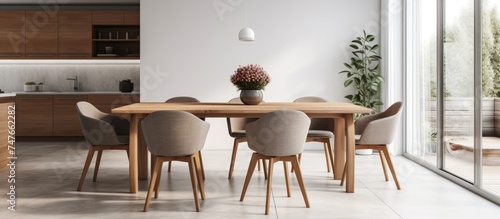 A wooden dining table is set in a dining room with four grey chairs around it. The room is well-lit  and the table is neatly arranged with place settings.
