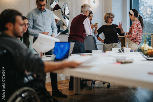 Inclusive work environment captured as a diverse team engages in a collaborative brainstorming session, showcasing teamwork and communication in an office setting with a person in a wheelchair.