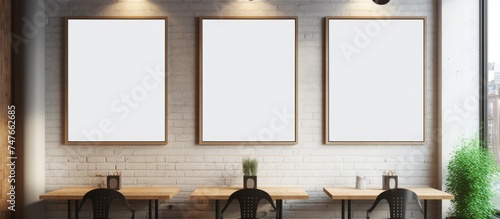 In a modern cafe interior, a row of tables is neatly positioned next to a white brick wall. Three blank vertical posters act as mockups for potential advertisements or decor.