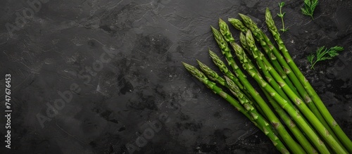 A stunning photo showcasing a bunch of vibrant green asparagus placed on a sleek black background.