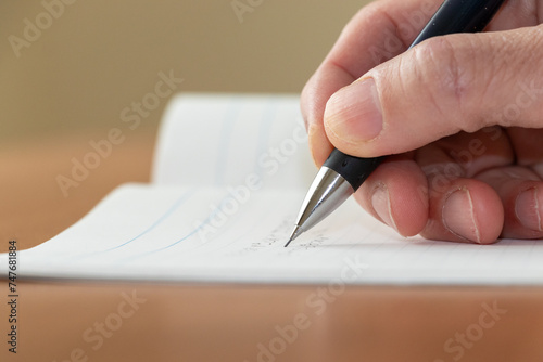 白いノートに何か書き込む人物の手
