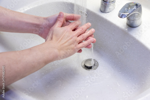 洗面台で両手を洗う人物