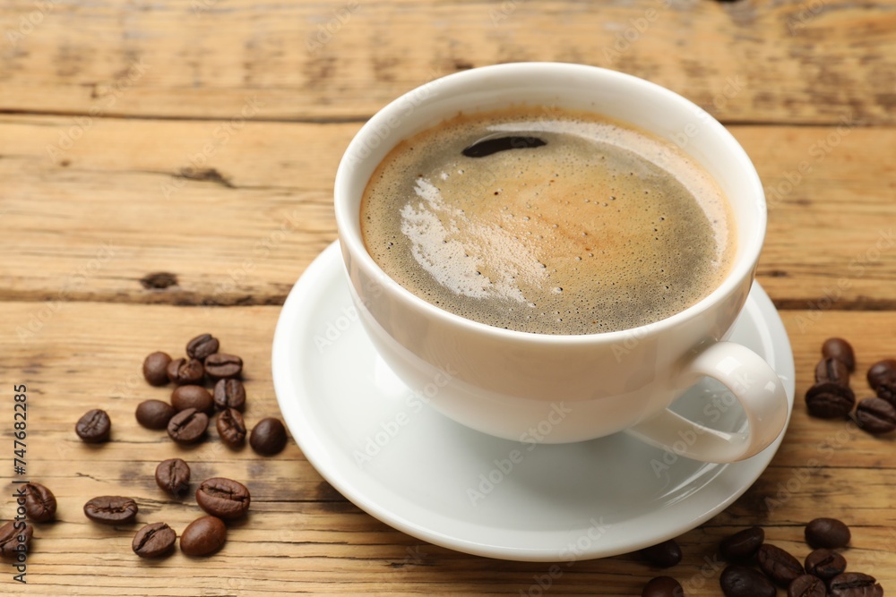 Cup of aromatic coffee and beans on wooden table, closeup Cup of aromatic coffee and beans on wooden table, closeup