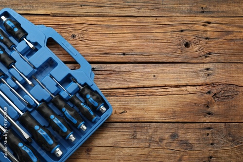 Set of screwdrivers in open toolbox on wooden table, top view. Space for text