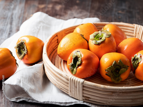 Persimmons on a wooden plate © mnimage