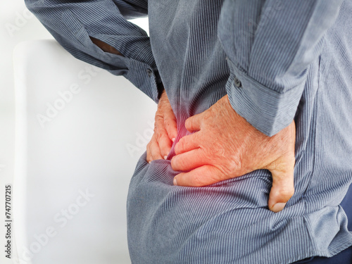 Old man suffering of backache, touching back with hand. Health care concept.